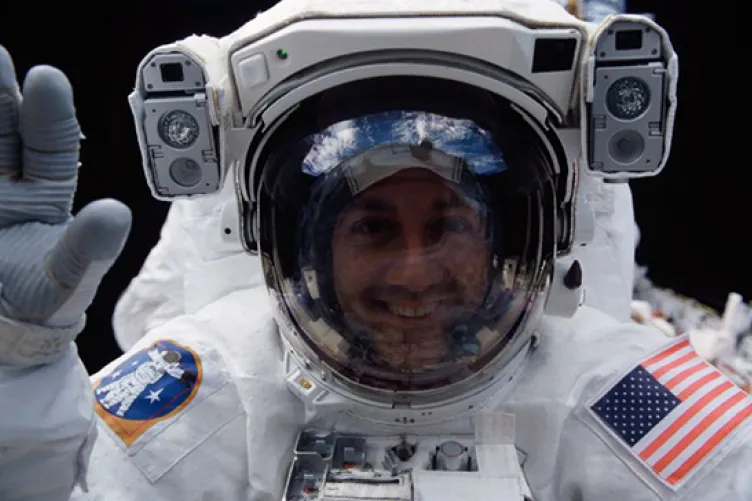 Astronaut Michael J. Massimino, STS-109 mission specialist, peers into Columbia's crew cabin during a brief break in work on the Hubble Space Telescope, latched down just a few feet behind him in Columbia's cargo bay, during his second extravehicular activity of STS109 on March 5, 2002. (NASA)