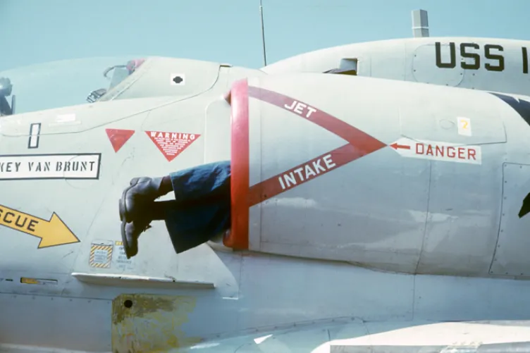 An archival photo of an airplane with two legs sticking out of a propeller.