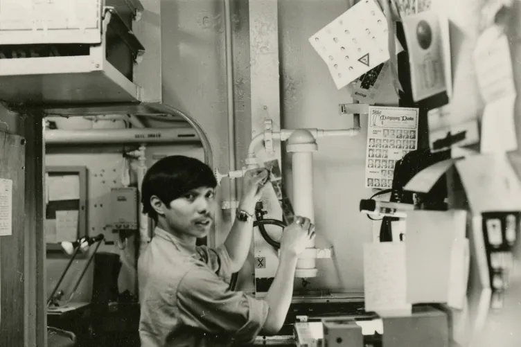 An archival photo of someone looking at a strip of film.