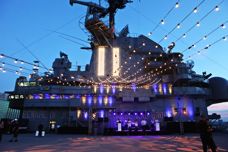 String lighting and uplighting is set with the band on stage with the Flight Deck Island as the backdrop