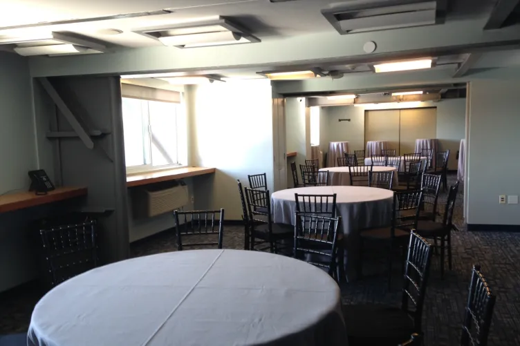 Classrooms set for an event with round tables, linen and black ballroom chairs