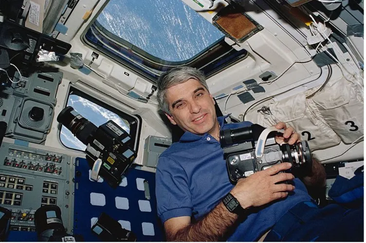 Astronaut and commander Sidney Gutierrez in Space Shuttle Endeavour, with a Hasselblad camera and a Casio databank 