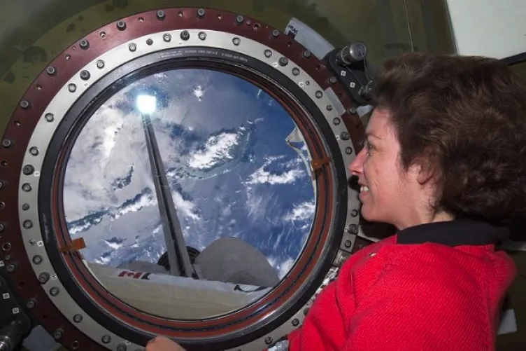 former astronaut Ellen Ochoa looking through a porthole in space.