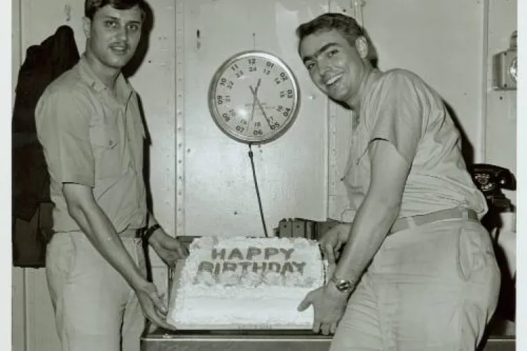 Two military personnel in uniform holding a birthday cake.