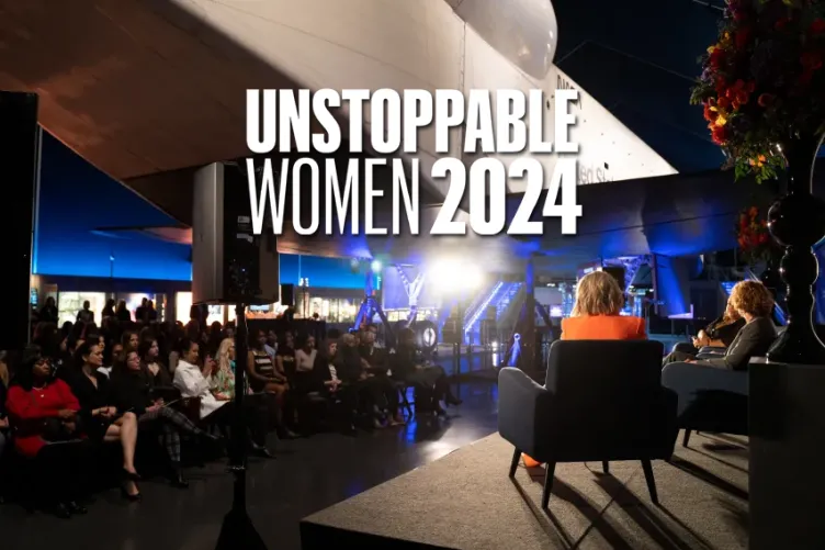 A diverse group of people seated beneath the Space Shuttle pavilion, gathered for a discussion.