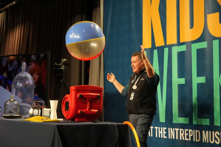 An educator on stage engaging a children in an interactive activity during Kids Week