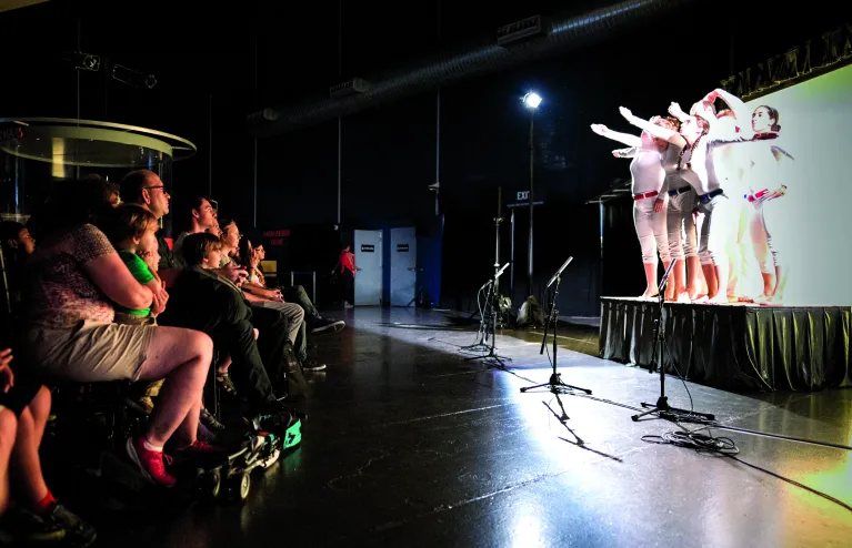 A group of visitors are seated watching a performance.