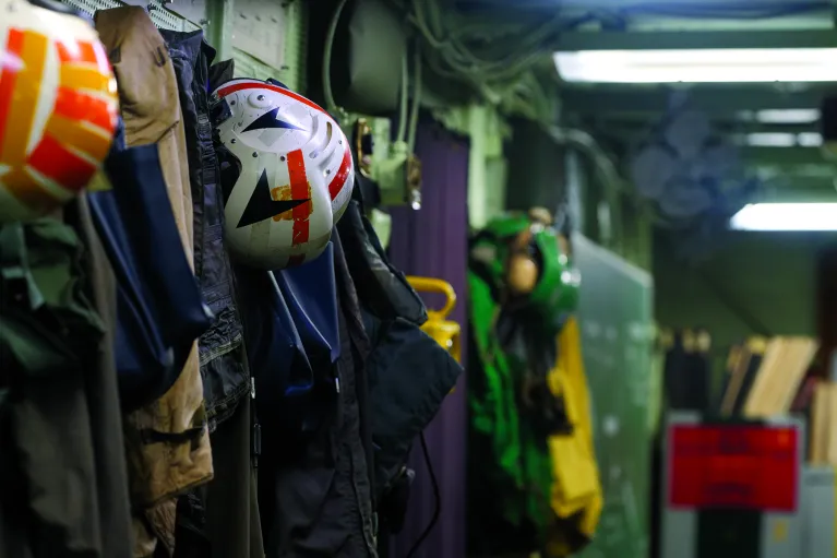 Various helmets and uniforms are hung up and ready for when soldiers need them.