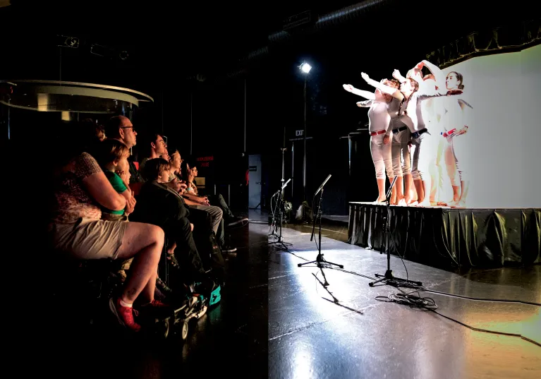 A group of visitors are seated watching a performance.