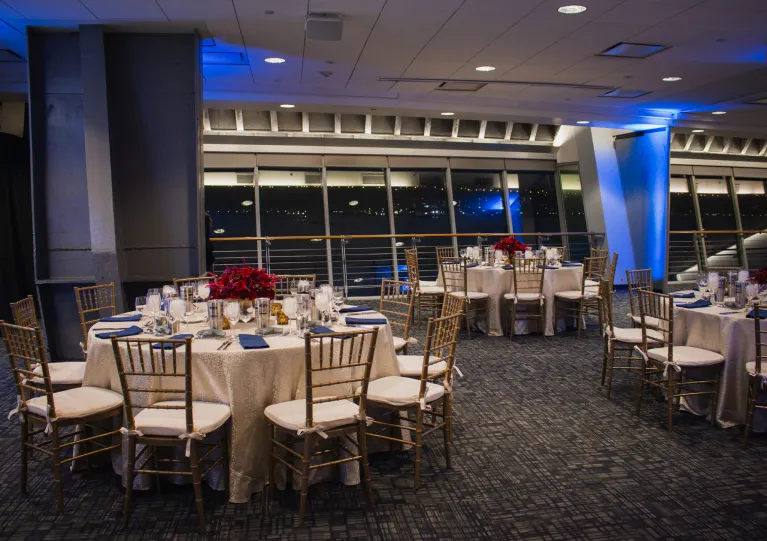 Dinner with blue uplighting and red floral arrangements on the dinner tables in the Great Hall