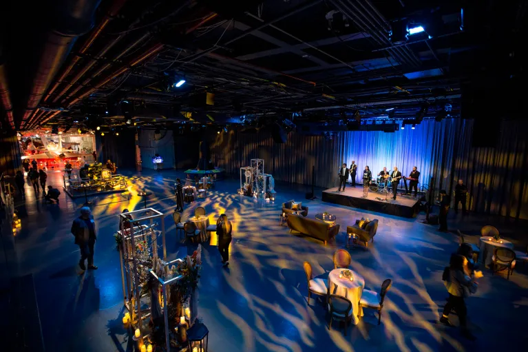 Cocktail reception in Hangar 3 with a band on stage and decorative high top and low top tables for guests