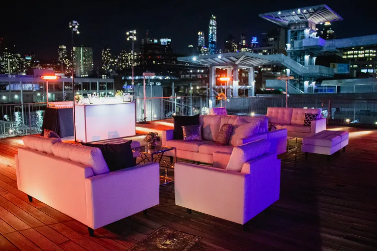 The port side aircraft elevator at flight deck level with lounge furniture for a cocktail reception with table top decor of flowers and a bar