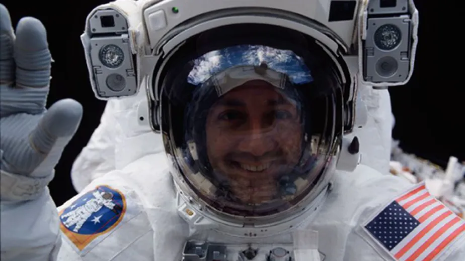 Astronaut Michael J. Massimino, STS-109 mission specialist, peers into Columbia's crew cabin during a brief break in work on the Hubble Space Telescope, latched down just a few feet behind him in Columbia's cargo bay, during his second extravehicular activity of STS109 on March 5, 2002. (NASA)