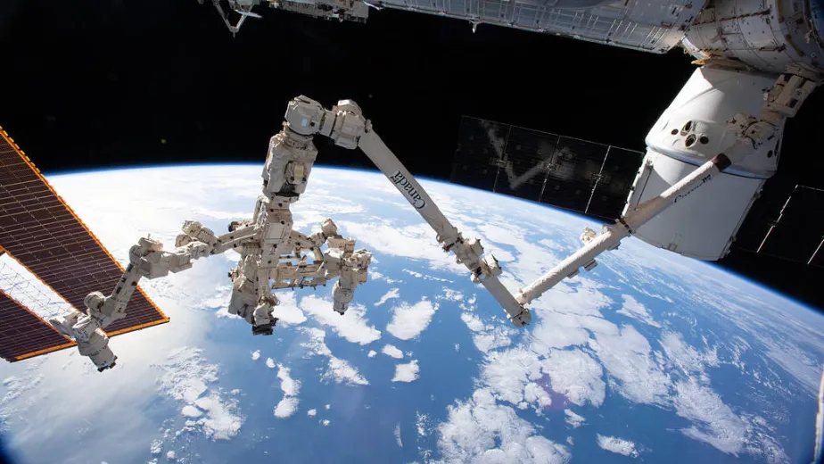 A robotic arm is outstretched over the Earth.