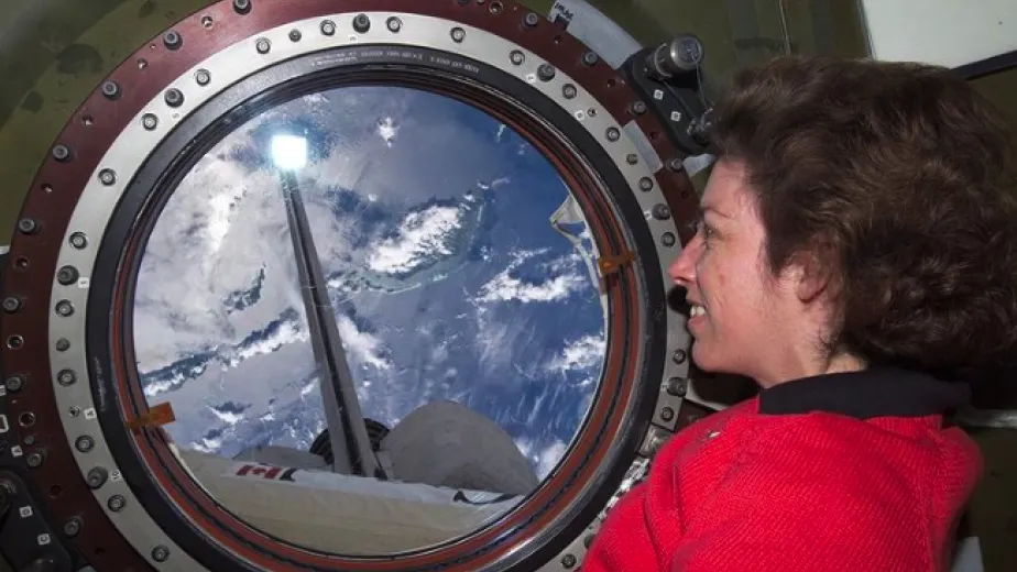 former astronaut Ellen Ochoa looking through a porthole in space.