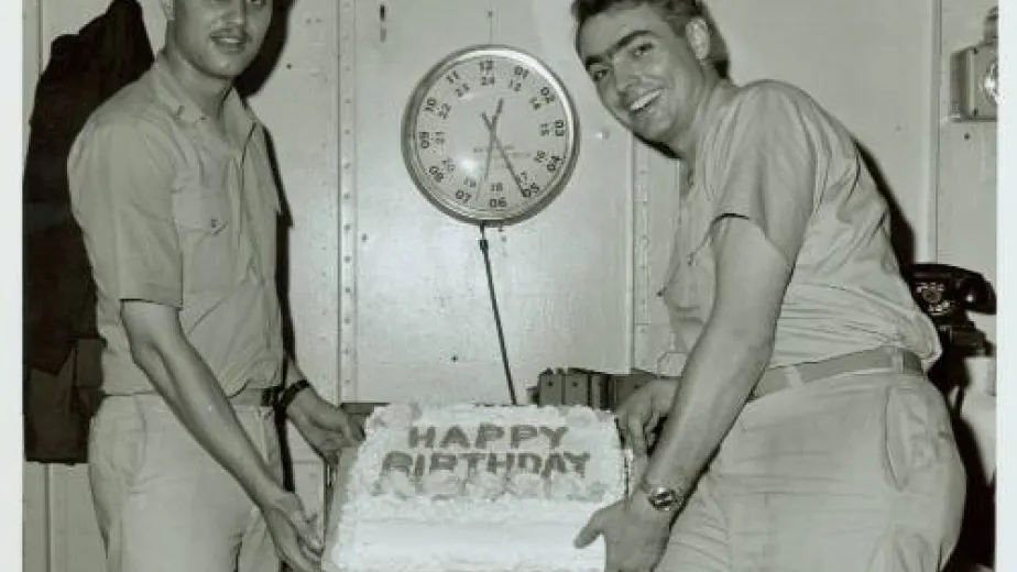 Two military personnel in uniform holding a birthday cake.