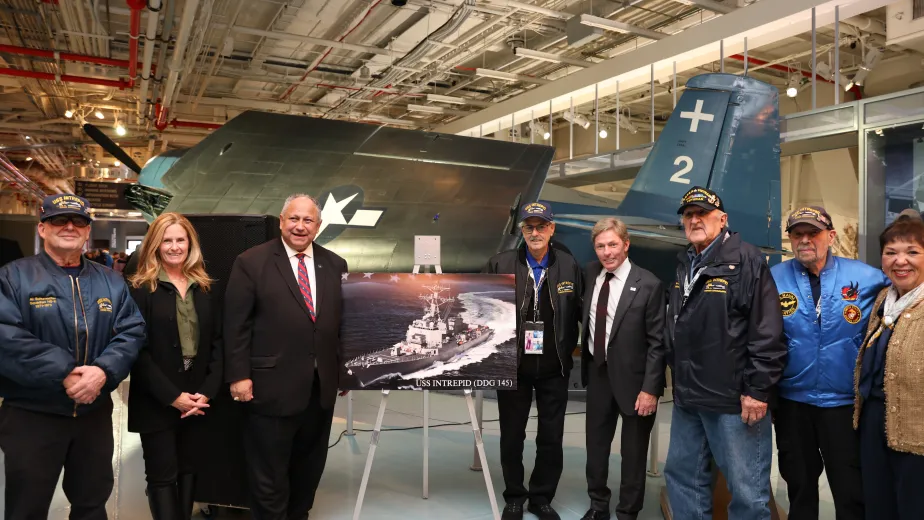 A group of people stand together on the hangar deck of the Intrepid Museum.